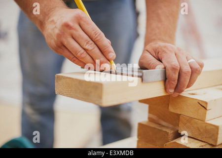 Caucasian construction worker marking wood planks Stock Photo
