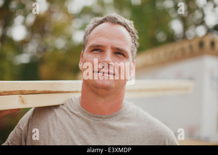 Caucasian construction worker carrying wood planks Stock Photo