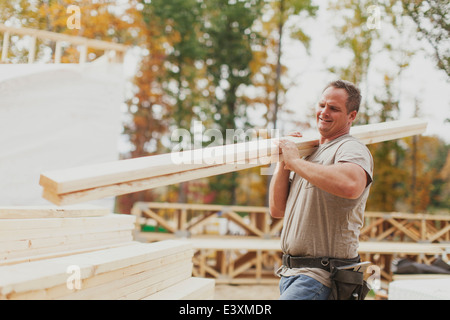 Caucasian construction worker carrying wood planks Stock Photo