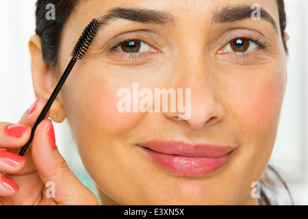 Mixed race woman applying makeup Stock Photo