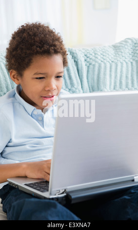Black boy using laptop in living room Stock Photo