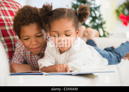 Black children reading together on sofa Stock Photo