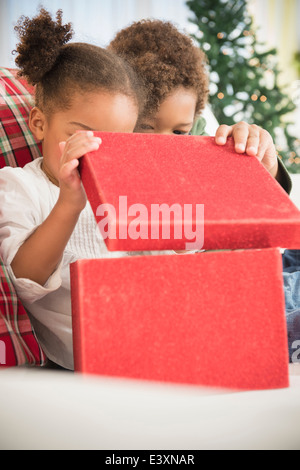 Black children opening Christmas gift on sofa Stock Photo