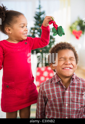 Black children playing with mistletoe in living room Stock Photo