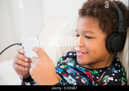 Black boy listening to headphones on sofa Stock Photo