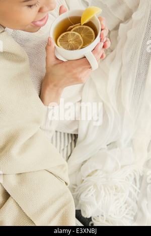 Black woman drinking cup of tea with lemon Stock Photo