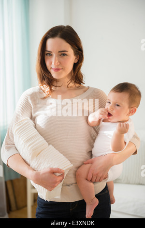 Mother holding baby and stack of diapers Stock Photo