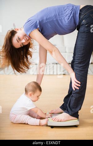 Mother with new baby standing on scale Stock Photo