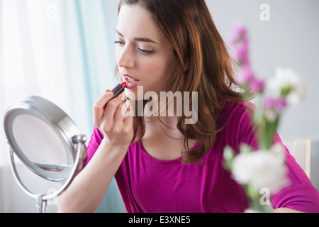 Woman applying makeup in mirror Stock Photo