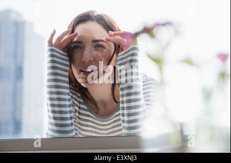 Woman peering in through window Stock Photo