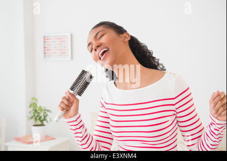 Mixed race woman singing into hairbrush Stock Photo