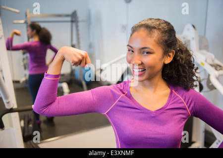 Mixed race woman flexing muscles in gym Stock Photo