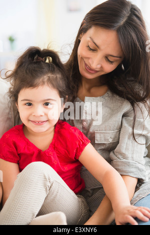 Hispanic mother and daughter sitting together Stock Photo