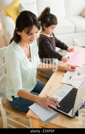 Hispanic mother and daughter working at table Stock Photo