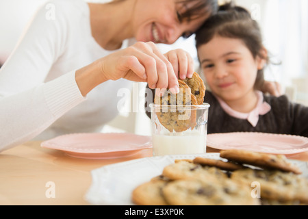 Hispanic mother and daughter dunking cookies in milk Stock Photo