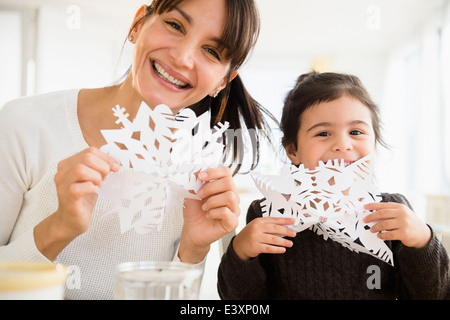 Hispanic mother and daughter making paper snowflakes Stock Photo