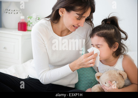 Hispanic mother wiping daughter's nose Stock Photo