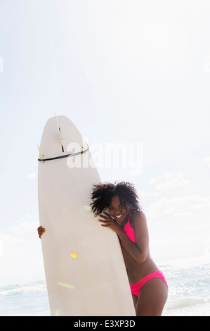 African American woman holding surfboard on beach Stock Photo