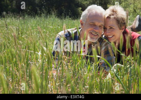 Senior Caucasian couple laying in tall grass Stock Photo
