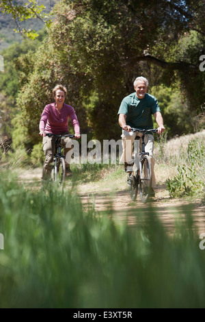 Senior Caucasian couple riding bicycles on rural path Stock Photo