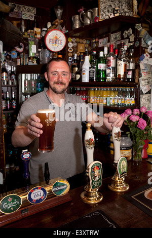 UK England, Suffolk, Bury St Edmunds, holding pint of IPA in Nutshell, Britain’s smallest pub Stock Photo