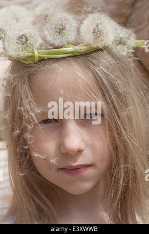 portrait of little caucasian girl in white dandelion garland Stock Photo