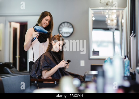 Stylist blow drying client's hair in salon Stock Photo