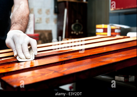 Varnishing and doing some sandpaper work on wooden boards Stock Photo
