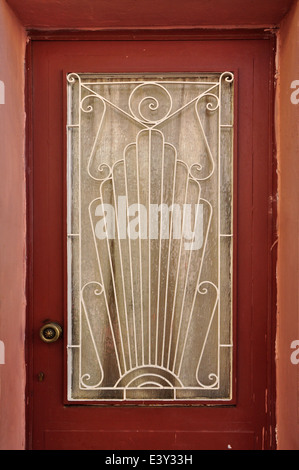Old wooden door glass lite screen decorated with iron pattern of abstract sun rays and spiral symbols. Stock Photo