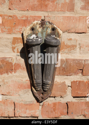 Flagstaff for two flags, very old, rusty and smeared paint on a brick wall. Stock Photo