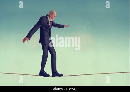 senior man walking on a tightrope or highwire balancing carefully Stock Photo