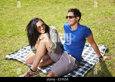 Couple sitting on picnic blanket in park Stock Photo