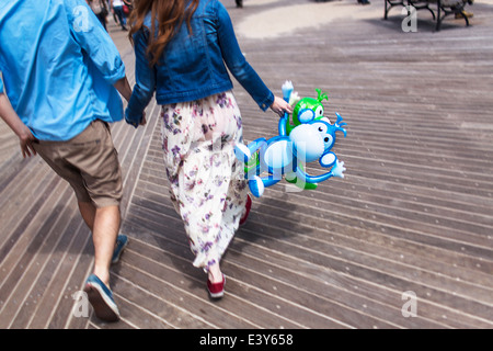 Cropped rear view of couple holding hands on boardwalk Stock Photo