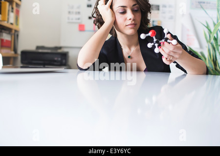 Young woman contemplating molecular model of Ethanol molecule