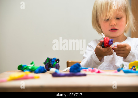 Three year old boy playing with modeling clay Stock Photo