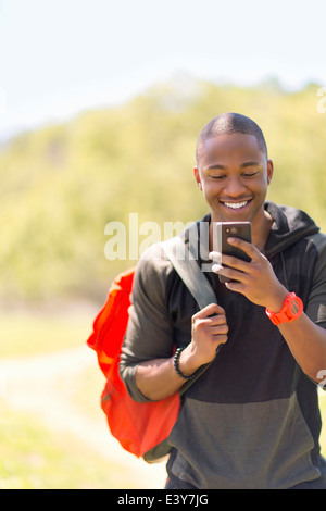 Young male hiker reading message on smartphone Stock Photo