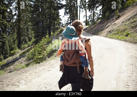 Rear view of mother carrying toddler in baby carrier Stock Photo