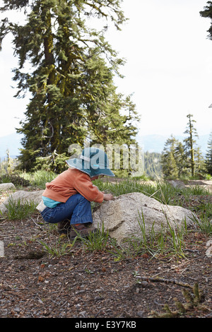 Toddler bending down to look at rock Stock Photo