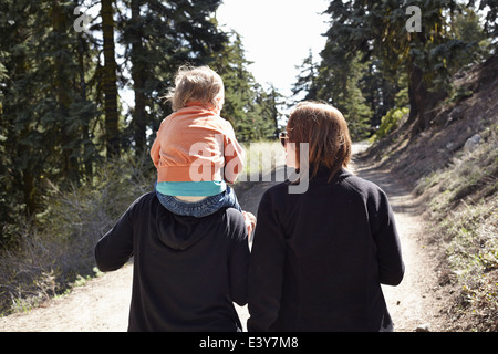Women walking through forest in Oregon, USA, with toddler sitting on shoulders Stock Photo