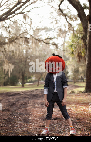 Portrait of boy in forest wearing pumpkin head