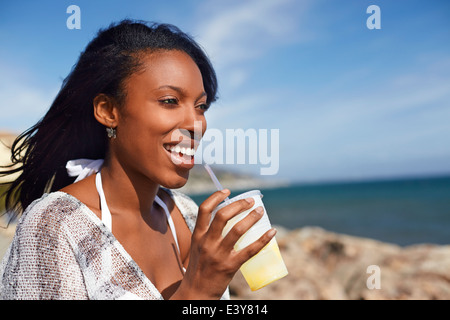 Young woman drinking fruit juice at beach, Malibu, California, USA Stock Photo