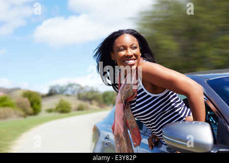 Young woman leaning out of moving car window Stock Photo