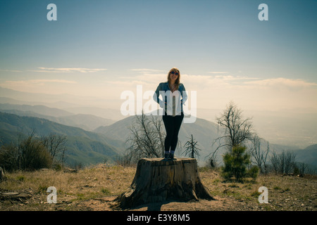 Portrait of mid adult woman standing on tree trunk, Lake Arrowhead, California, USA Stock Photo