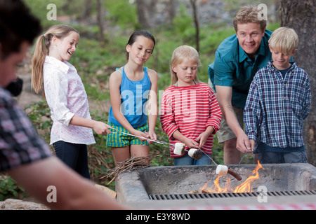 Mature couple and four children toasting marshmallows on campsite, Sedona, Arizona, USA Stock Photo