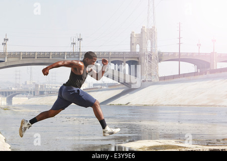 Young man speed running and jumping from riverbank Stock Photo