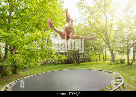 Teenage girl jumping on trampoline, outdoors