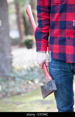 Cropped image of mid adult man in forest holding an axe