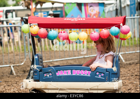 Pilton, UK, 29/06/2014 : Celebrities and atmosphere in the backstage area at Glastonbury Festival . A young girl in a 'Jake Buggy' buggy. Picture by Julie Edwards Stock Photo