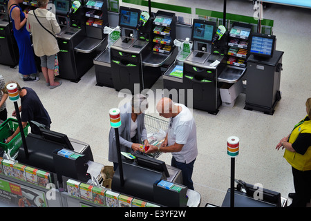 Elderly couple using self checkout till in supermarket Stock Photo