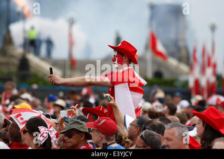 Ottawa, Canada. 1st July, 2014. A spectator takes a photo in the background during the ceremonies to celebrate the 147th Canada Day on Parliament Hill in Ottawa, Canada, on July 1, 2014. Credit:  David Kawai/Xinhua/Alamy Live News Stock Photo